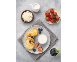 cheesecakes or cottage cheese with fresh blerries, sour cream and milk on a gray background. the concept of healthy and delicious breakfast